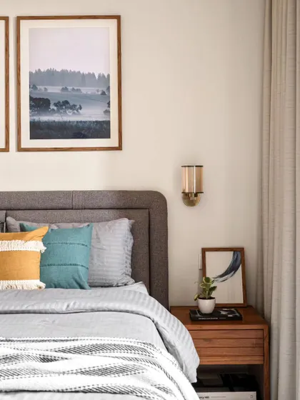 A bedroom should reflect your personality, right down to the bedside table. This setup is simple yet stylish, with a warm wood table, a modern sconce for reading, and personal touches like art and a small plant.