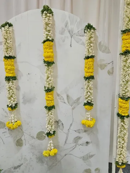 A close-up of the fresh flower garlands. We use fragrant jasmine (malli) and vibrant yellow marigolds, carefully woven together to create these beautiful decorative strands for the Noolukettu backdrop.
