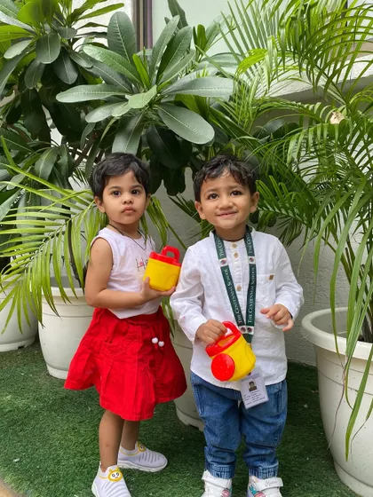 Two proud gardeners with their watering cans. This activity not only teaches them about plant life but also helps develop their gross and fine motor skills.
