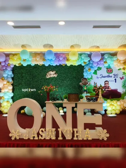 This Cocomelon setup for a first birthday uses a grass backdrop and large letter blocks to create a playful and photogenic scene.