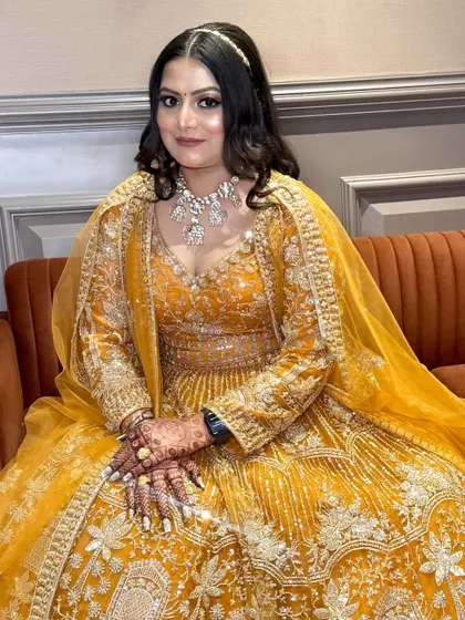 A seated portrait of the bride in her yellow outfit, her makeup perfectly complementing the warm tones.