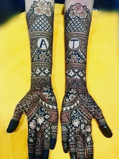 This design features the initials 'A' and 'T' prominently on each arm, surrounded by a beautiful mix of floral and geometric bridal patterns.