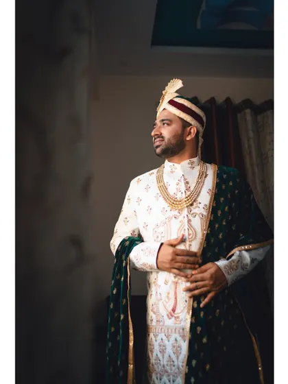 A classic portrait of the groom on his wedding day. Dressed in a white and gold sherwani with a velvet shawl, he looks regal and ready for the big moment.