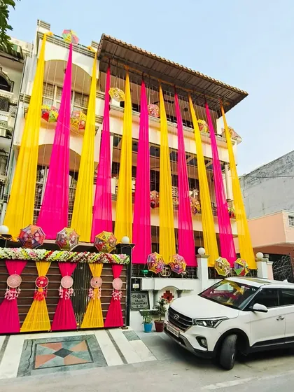 Wedding celebrations often start at home, and I ensure they are just as beautiful. Here's a full home exterior I decorated with bright pink and yellow drapes and traditional elements for a festive feel.