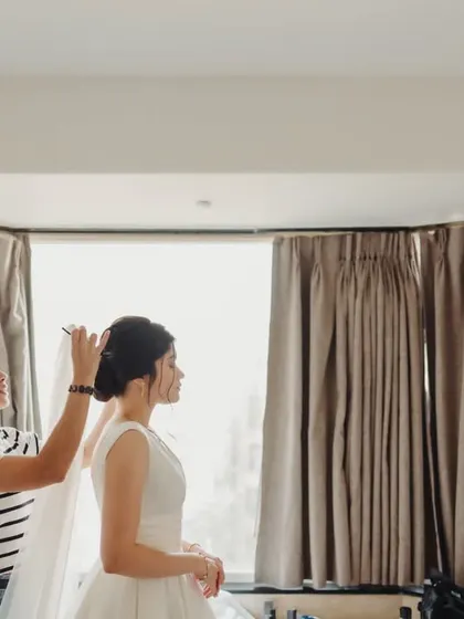 Here I am, adding the final touches. This is a glimpse into my process, making sure every detail, like placing the veil on this classic updo, is perfect before the bride walks down the aisle.