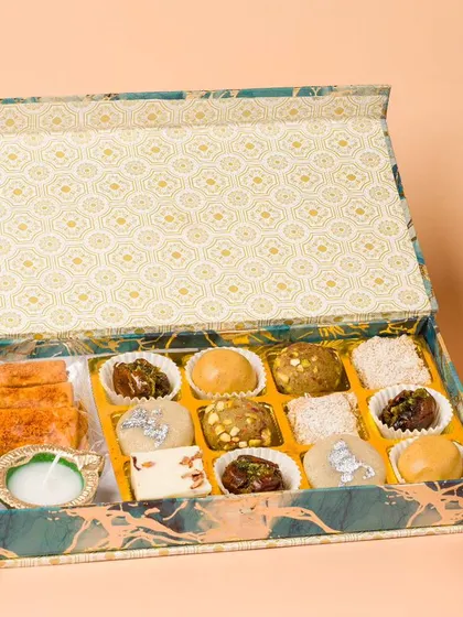 An open box of assorted Indian sweets, styled for a Diwali catalogue. We arrange each sweet carefully to showcase the variety and craftsmanship.
