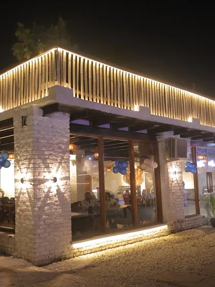 The exterior view of our indoor dining hall at night. The large glass windows offer a great view of the outdoor lawns and pool.