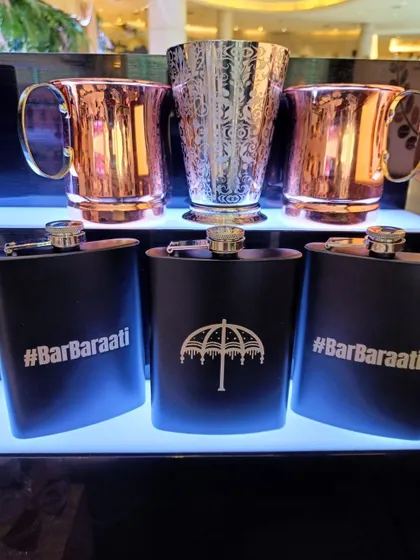 I can create custom merchandise and party favors for your guests. This display shows personalized hip flasks alongside elegant copper and silver mugs, making for a stylish and memorable wedding giveaway.