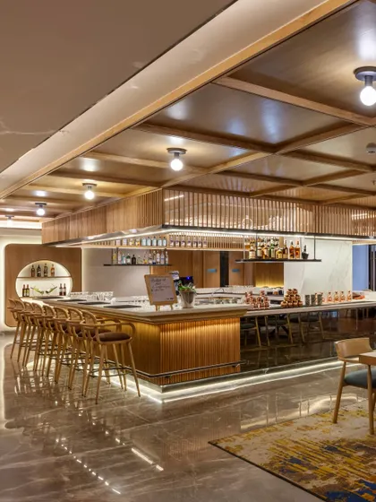 The expansive bar and lounge area at Radisson Resort, designed to be a central social hub. The space features a long, elegant bar with comfortable seating, coffered wood ceilings, and a material palette that reflects an 'urban resort' philosophy.