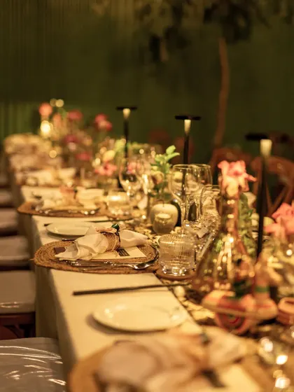 A long dining table set with floral runners and candles, creating a warm and inviting atmosphere for a sit-down dinner.