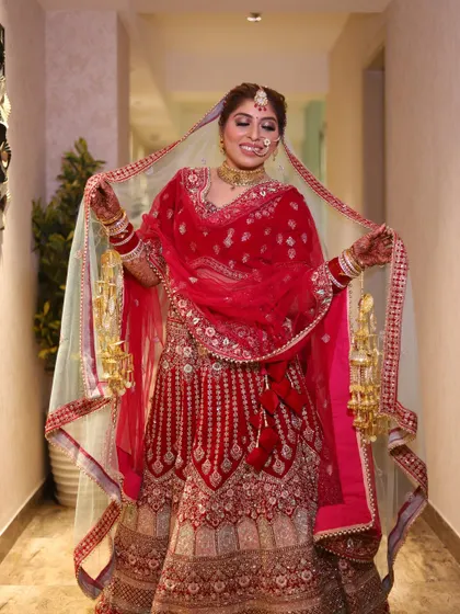 A full-length portrait of the bride in her stunning red lehenga, holding her veil. We capture the complete bridal look in elegant poses.