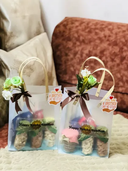 Rakhi gift bags for brothers, filled with jars of dry fruits and adorned with floral details and a "brother like no other" tag.