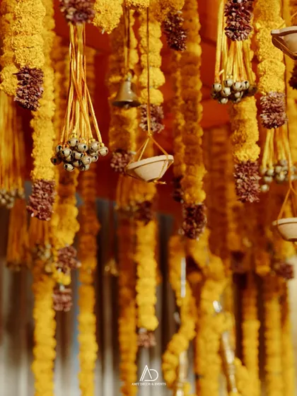 A detailed shot of the hanging decor, featuring strings of marigolds accented with small brass bells and other traditional elements.