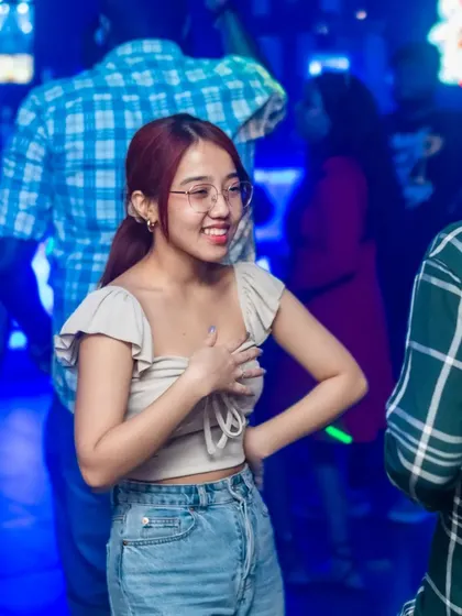 A guest smiling and chatting with a friend amidst the blue-lit dance floor. It's a social hub, not just a place to dance.