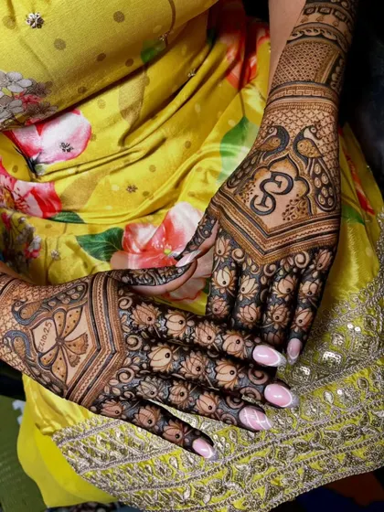 A close-up of a beautiful back-hand design. This pattern features a delicate butterfly, a lotus, and the Om symbol, combining different elements into a cohesive piece of art.