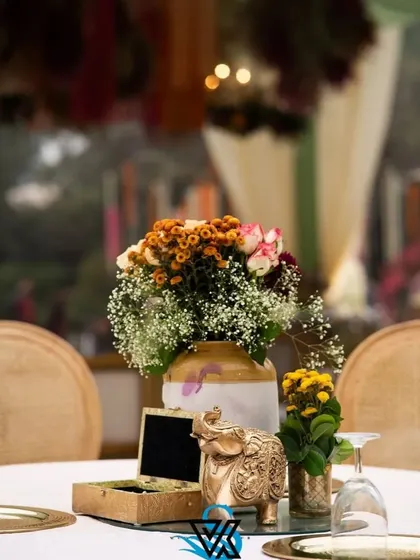 A simple yet elegant table setting, featuring a small floral arrangement, a custom-made box, and a beautiful golden elephant figurine.