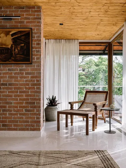 An exposed brick wall and a pine wood ceiling create a warm, rustic-industrial feel in this sun-drenched corner. The classic planter's chair is the perfect spot to enjoy the view.