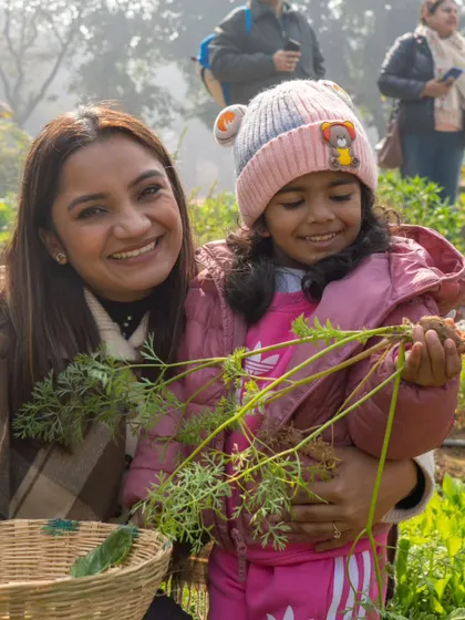 A mother and daughter share a happy moment while harvesting carrots. These shared experiences are what make a family trip to the farm so memorable.