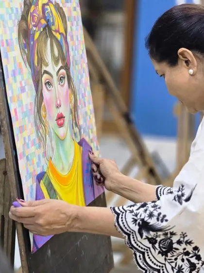 An artist carefully places her colorful oil pastel portrait on an easel, a piece defined by its vibrant palette and a unique pixelated background.