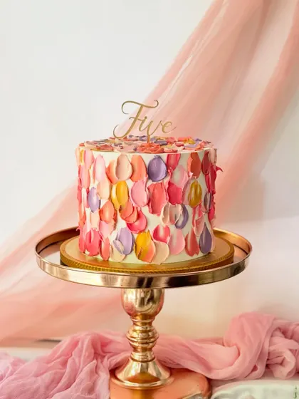 A beautiful cake showcasing the palette knife technique. The colorful petals create a textured, impressionistic design, topped with a delicate gold "Five" script.