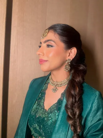 A portrait of the bride, her elegant fishtail braid and maang tikka creating a stunning and contemporary look.