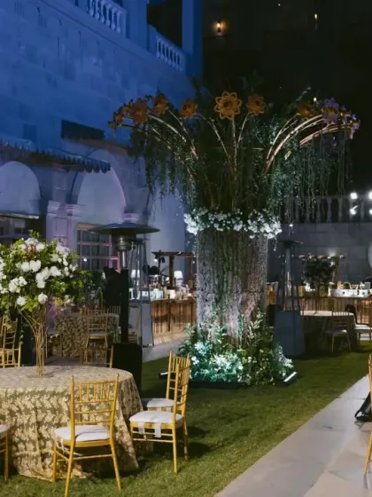 An outdoor lounge area for the sangeet, featuring a stunning bar with a large floral tree centerpiece and an elephant ice sculpture.