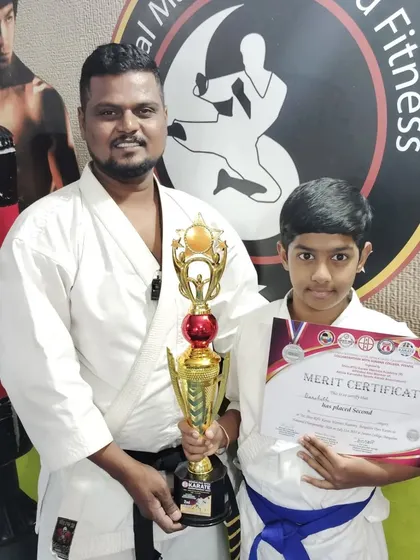 A second-place win for this blue belt student, proudly holding his certificate and trophy.