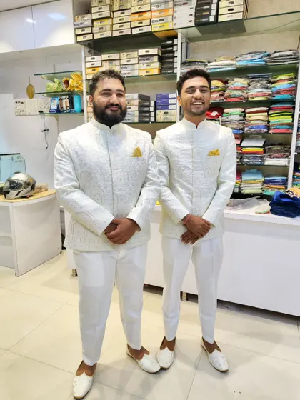 A full-length photo of the two clients in their matching white Jodhpuri suits, looking sharp and coordinated.