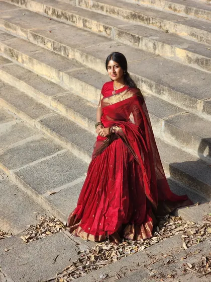 The full view of our viral deep red half saree. The voluminous skirt and the elegantly draped dupatta create a silhouette that is both grand and graceful, perfect for a high-end wedding or reception.