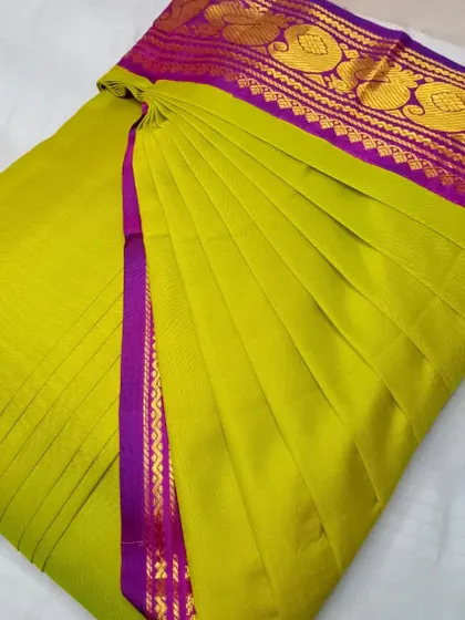 A bright lime green saree with a purple and pink border. The pleats are crisp, and the saree is ready to be draped in less than five minutes.