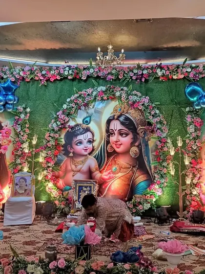 A full view of the main pooja area for the Krishna-themed godh bharai. The setup includes a central backdrop for the ceremony, flanked by two other large character illustrations.