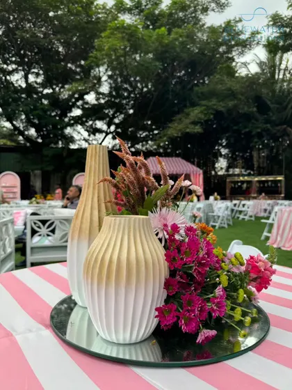 Playful table decor for an outdoor event, with pink and white striped linens and simple, modern centerpieces.