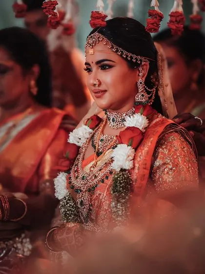 A portrait of a bride seated at the mandap, her expression calm and poised. This shot focuses on her traditional jewelry and the serene atmosphere of the Hindu wedding ceremony.