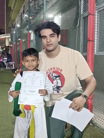 A young boy receives his green and yellow belt. He is moving up the ranks through consistent effort.