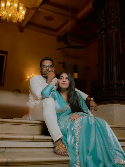 A regal and poised portrait of the couple seated on the grand staircase of a heritage building, surrounded by opulent interior details.