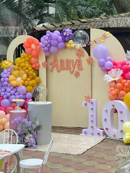 The main backdrop for a 10th birthday with a floral and artsy theme. The setup features a large '10' marquee light and a beautiful balloon arrangement, creating a perfect photo spot.