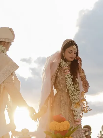 The setting sun backlights the couple as they perform their wedding rituals by the sea.