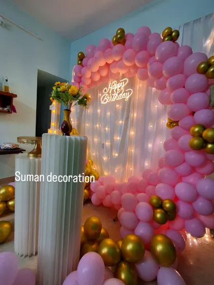 A close-up view of the pink and gold balloon ring and the glowing 'Happy Birthday' neon sign.