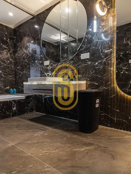 A glimpse into a bathroom designed for ultimate relaxation. We used dramatic black marble for the walls and a large, modern mirror to create a spa-like experience, handling all tiling and fixture installation.