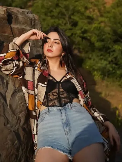 On fire, but still feeling fine. A powerful pose in a casual-chic outfit featuring a bralette, denim shorts, and a printed shirt.