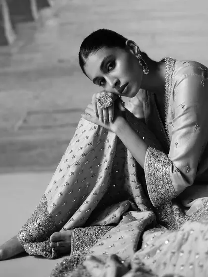 A black and white shot that emphasizes the texture and emotion of the moment. This artistic approach highlights the intricate sequin work on the pants and the model's contemplative pose.