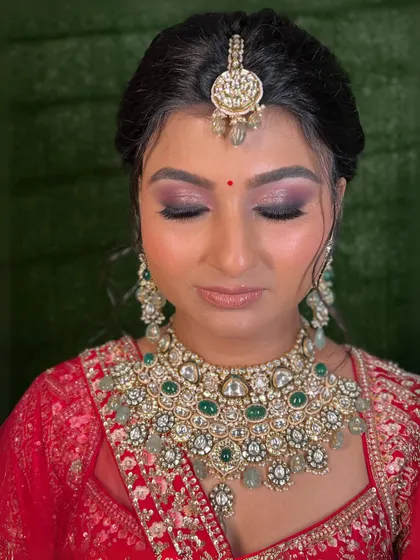 A close-up of the eye makeup. The deep purple and pink tones add a touch of modern drama to the classic red lehenga.