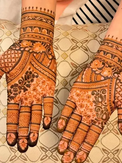 A full view of a matching set of mehndi for both hands. The palm has a dense floral and jaali pattern, while the back of the hand features a beautiful lotus mandala.