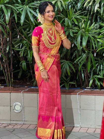 This bride is a vision in pink. Her vibrant Kanjivaram saree and extensive gold jewellery create a look of pure bridal magnificence.
