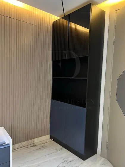 A tall, modern storage cabinet in a bedroom. The design combines open shelving with fluted glass and solid doors, offering a mix of display and concealed storage options.
