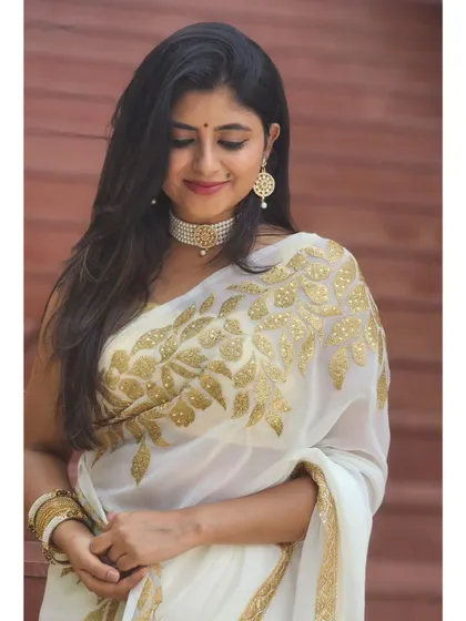 A candid, happy moment in the white and gold embroidered saree.