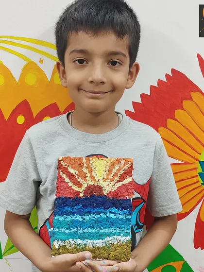 A close-up of a student's vibrant paper mache artwork. The texture of the paper pulp adds a wonderful three-dimensional quality to the sunset over the ocean.