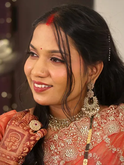 A close-up of the bride's radiant reception makeup. The look features warm tones, a defined red lip, and a touch of shimmer on the eyes.