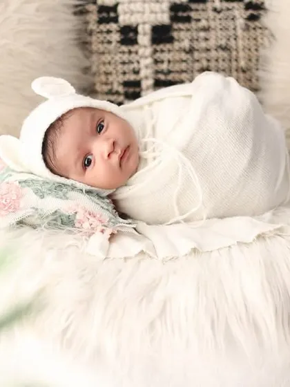 Wrapped cozily in white, this alert baby looks right at the camera. These awake moments are precious and show a different side of your baby's first weeks.