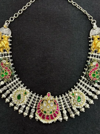 A beautiful fusion necklace set featuring camel and peacock motifs. The design mixes oxidised silver with gold-plated accents and colourful Kundan work, creating a piece that's rich in detail and tradition.